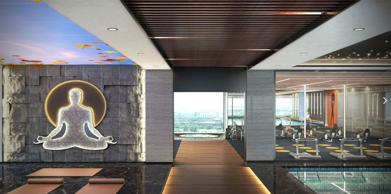 Yoga studio with stone Buddha mural beside a glass-walled gym corridor